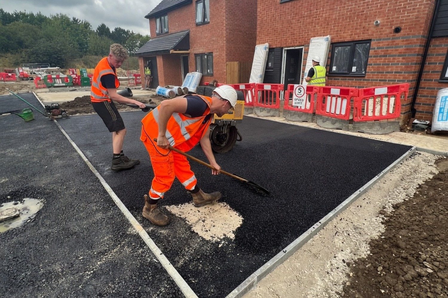 Two operatives hand-laying hot asphalt at a new-build housing development