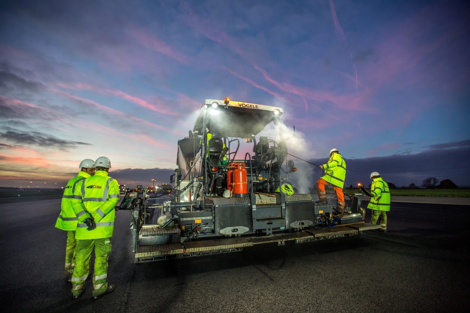 Paver in operation under floodlights during a night-shift resurfacing job