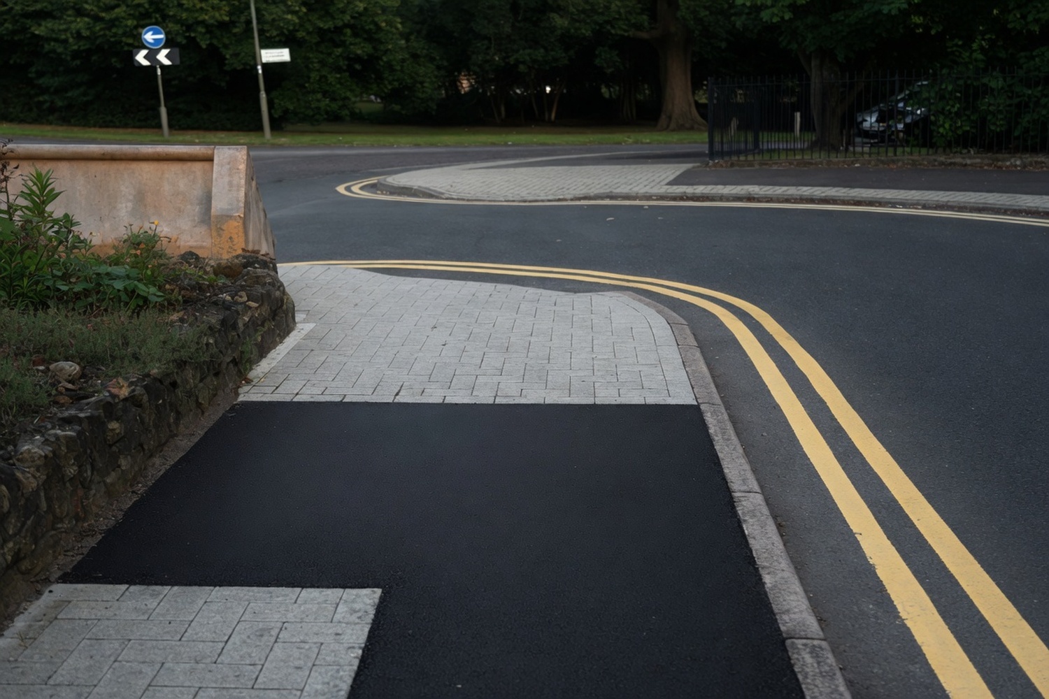 Finished hot-mix asphalt patch on a road curve with new double-yellow markings