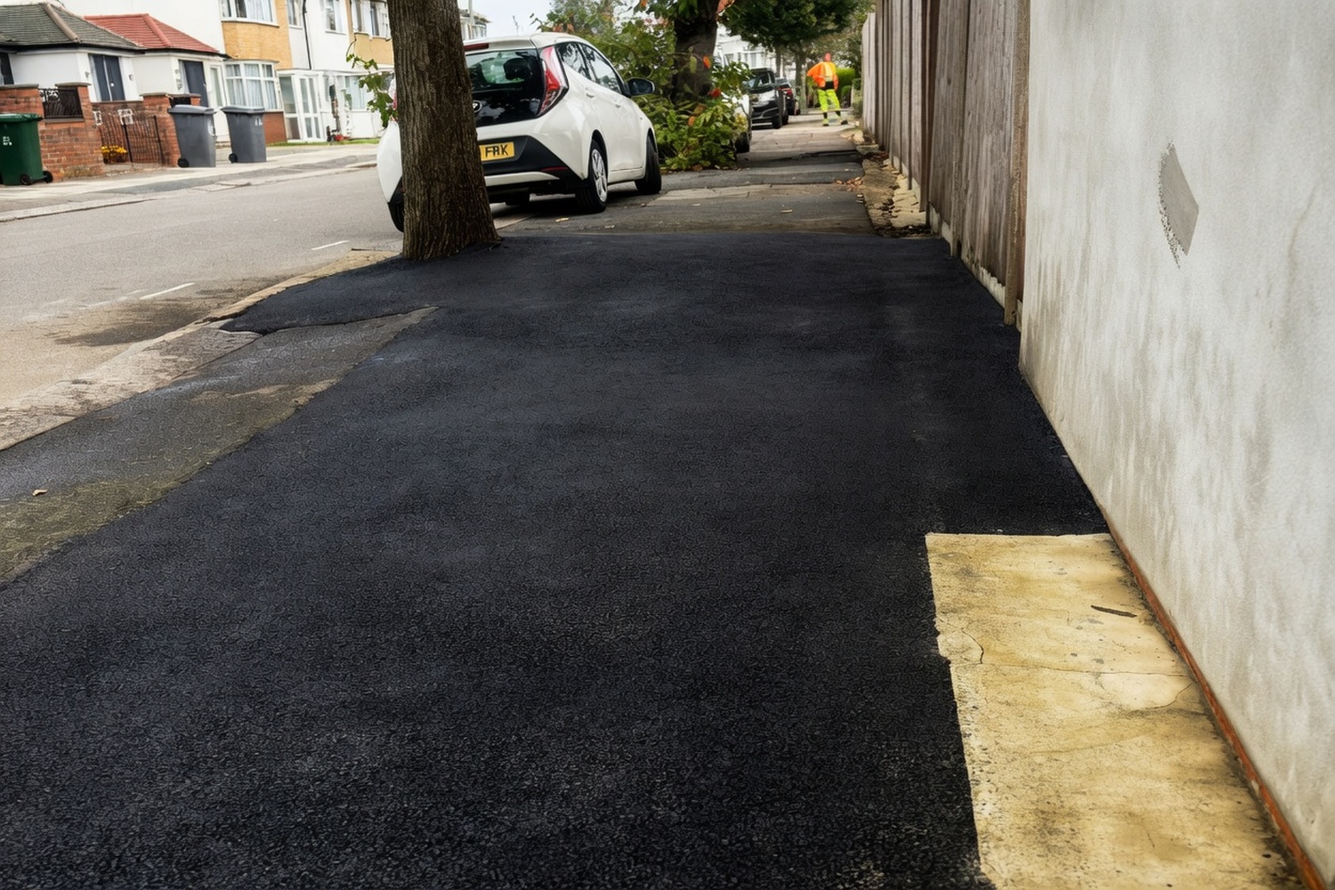 Asphalt path patch repair beside a brick wall